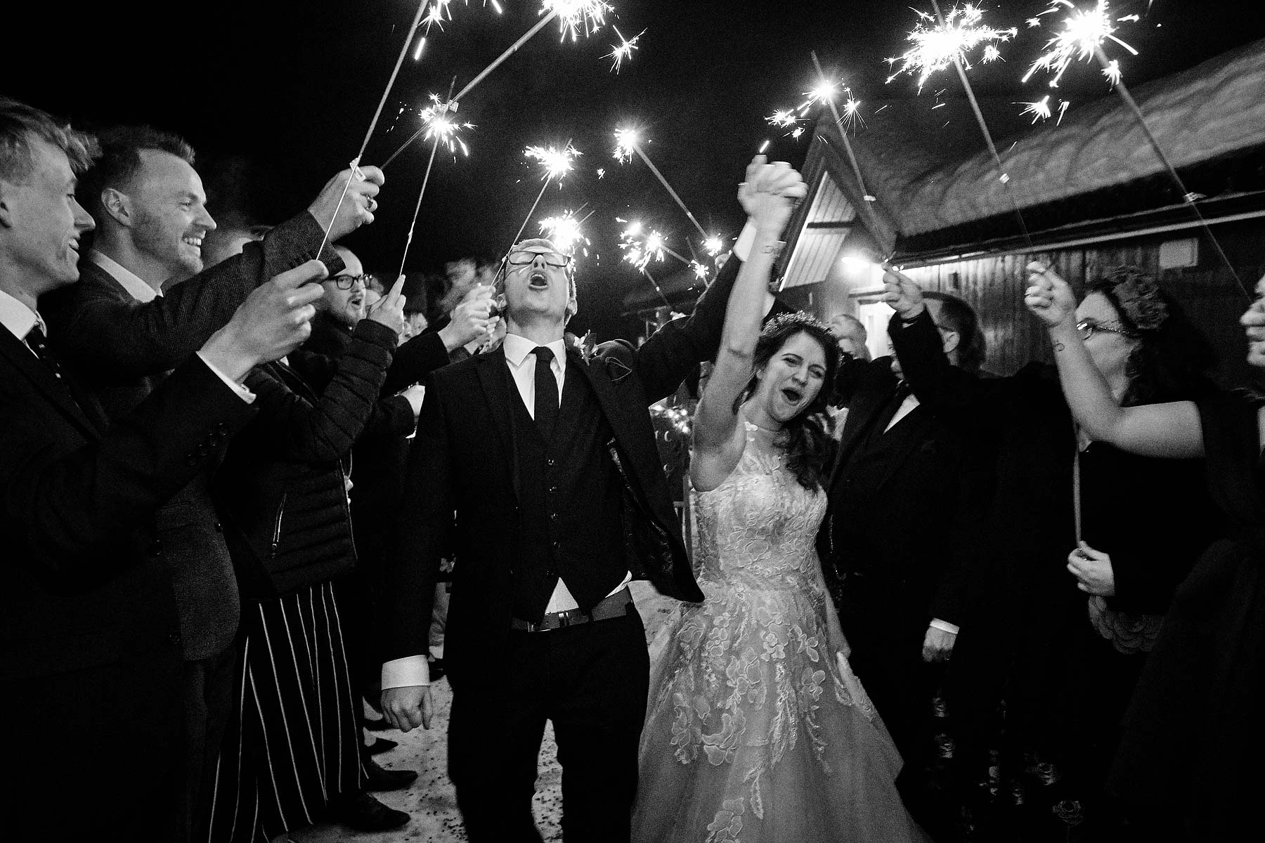 Creative storytelling wedding photography - great moment as bride and groom leave under canopy of sparklers